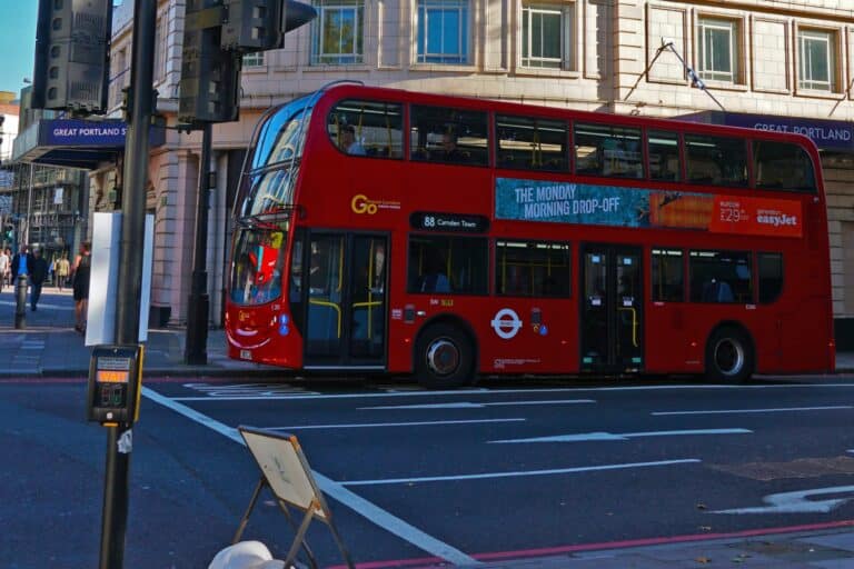 A double-decker bus picking up passengers from a bus stop in the concept of 'how to use Fulham's public transport for new homeowners'.