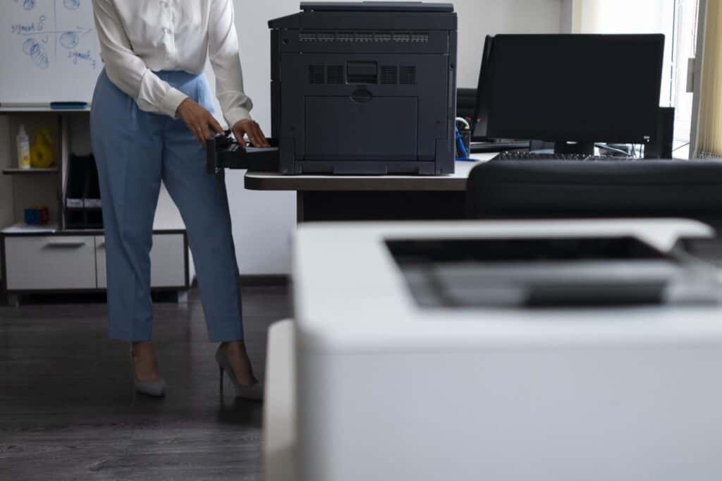 Cropped image of a female employee in the office's printing area with printers and scanners