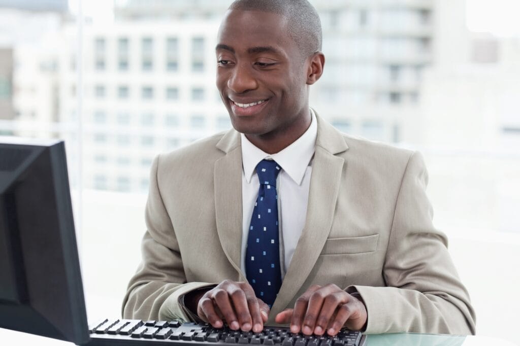 A smiling male employee is using the computer to announce the office move.